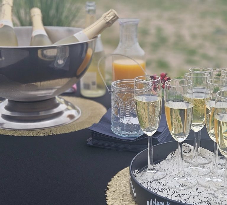 Elegant gedeckter Tisch mit Gläsern, einem Blumenarrangement und weißen Servietten.